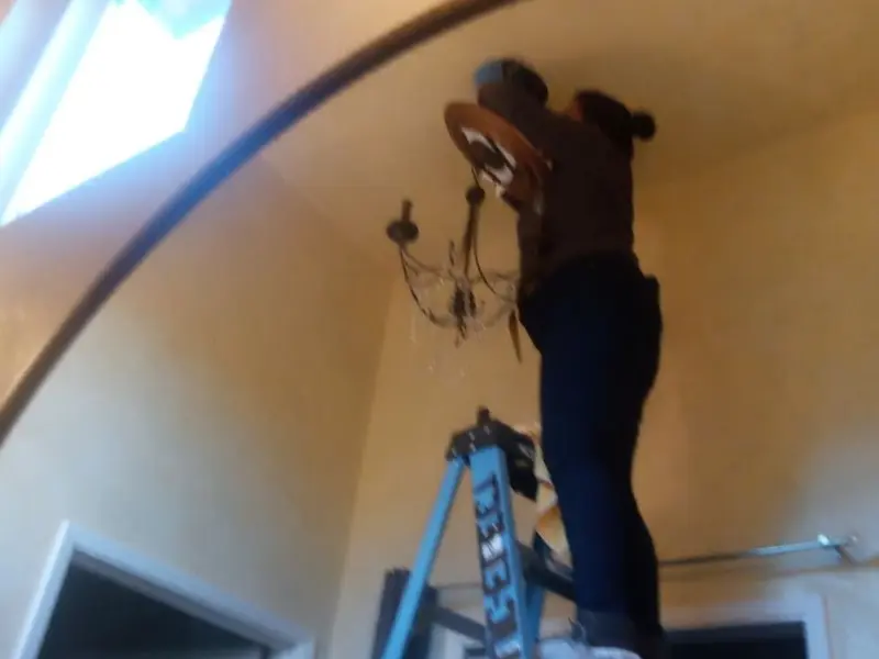 Electrician installing a chandelier in a Malabar residence